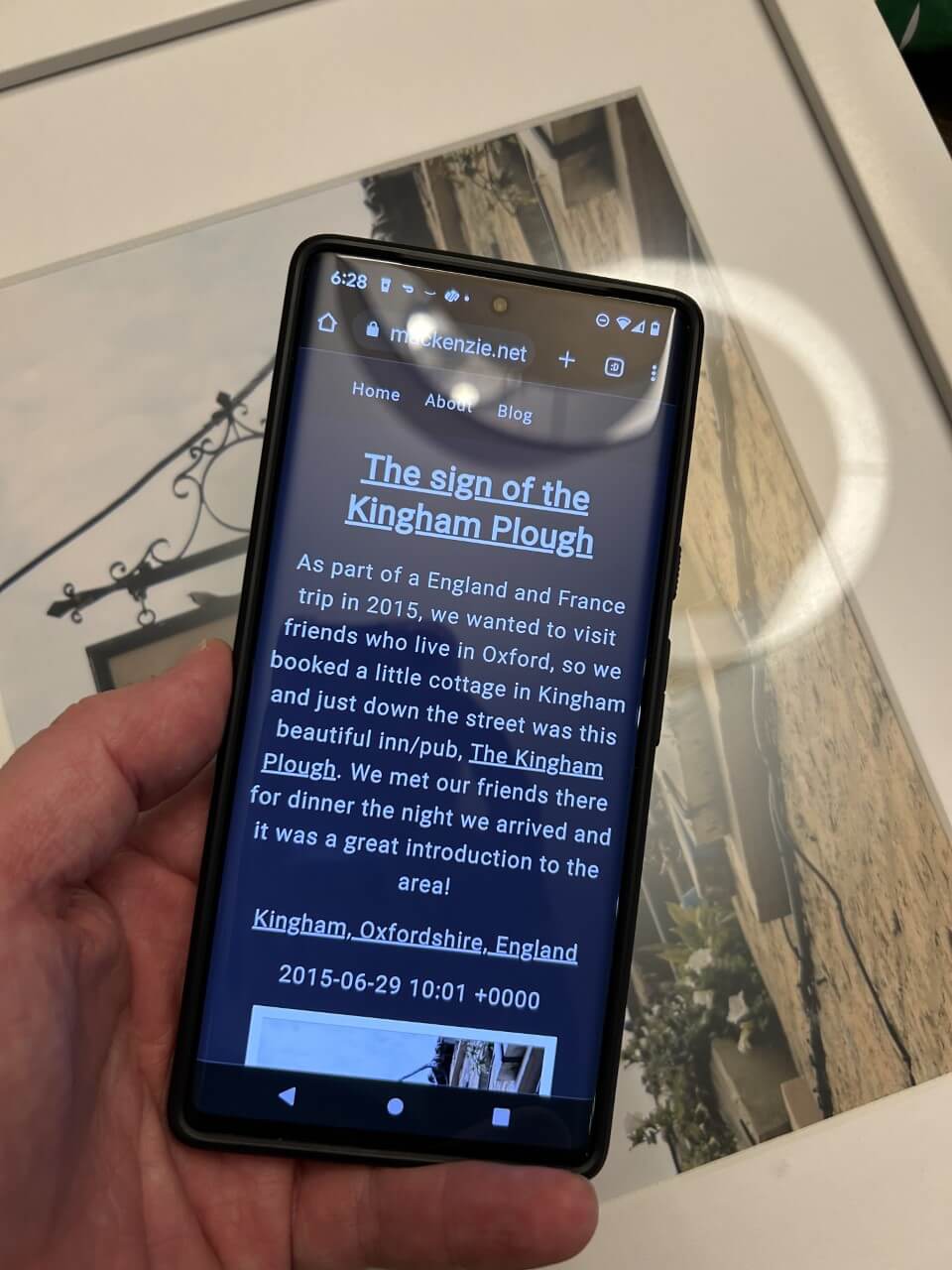 shot of an android phone held near the picture frame, photo info page visible on the device